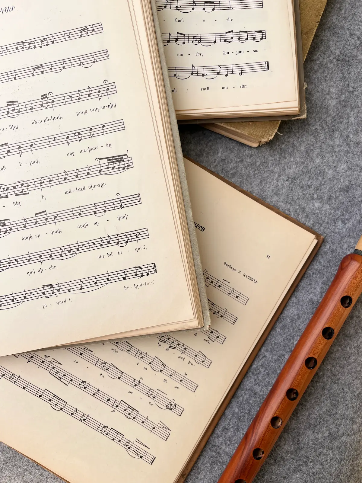 Open Armenian songbooks with sheet music beside a wooden duduk